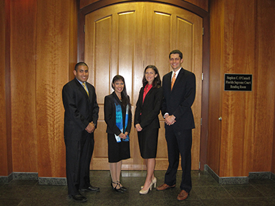 4 professionals in business attire in front of large interior door